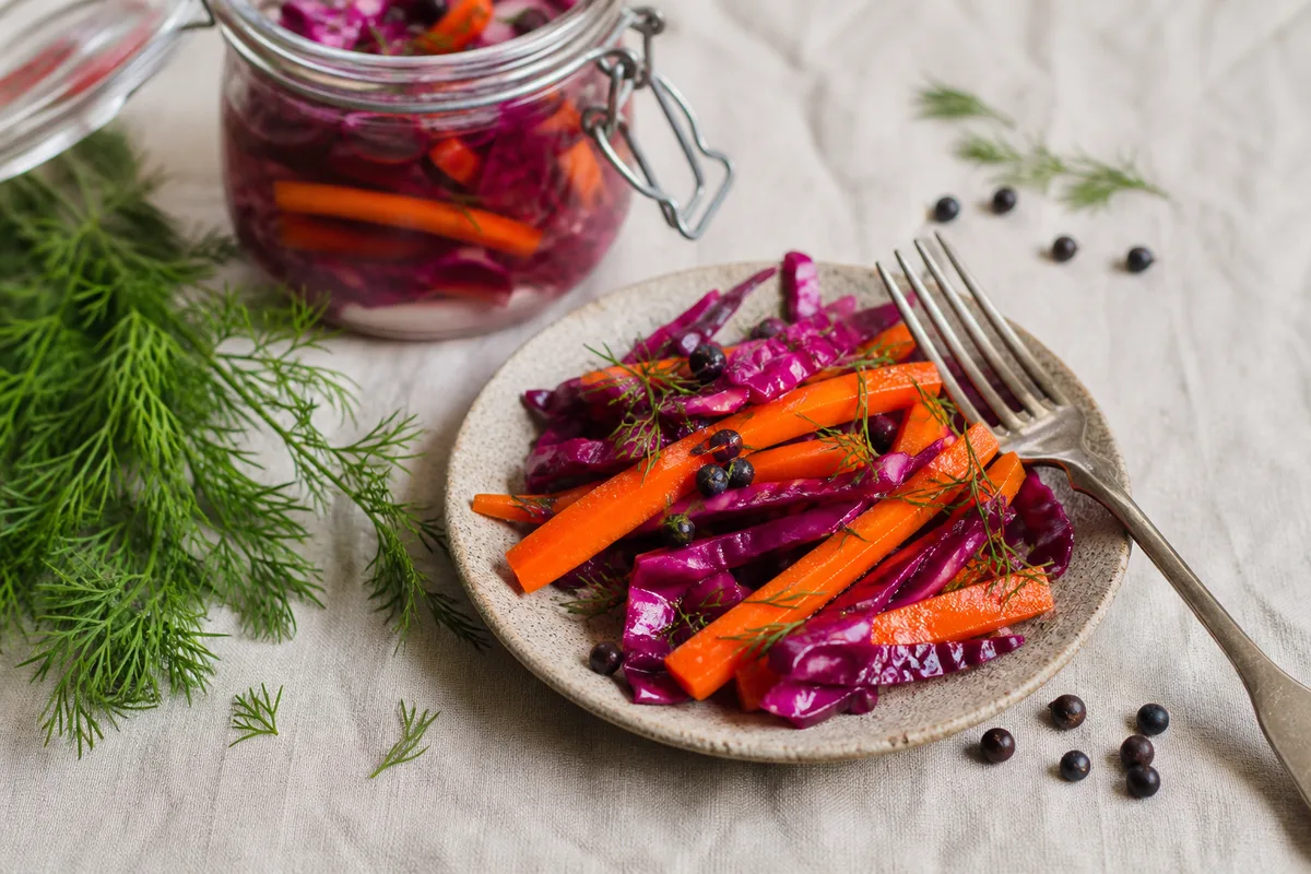 Assiette de bâtonnets de carottes fermentées et de chou rouge servis en condiment